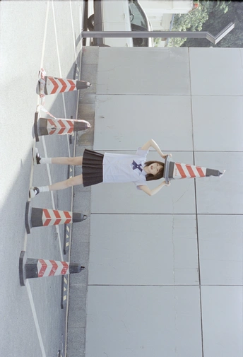 一位年轻女子站在梯子旁边 紧邻墙壁 手里拿着滑板。