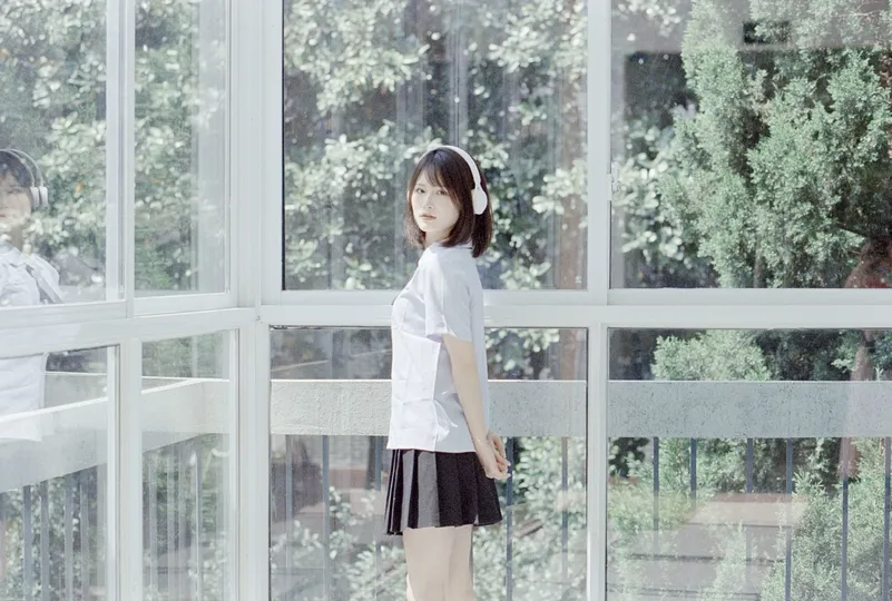 一个穿着高中制服的年轻女孩正在窗前向外看