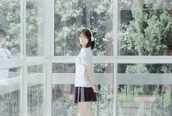 一个穿着高中制服的年轻女孩正在窗前向外看