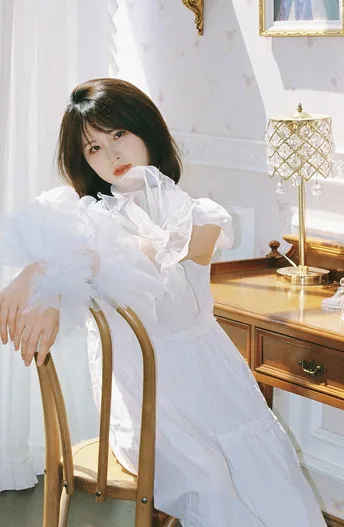 一个穿着白色连衣裙的女孩坐在椅子上