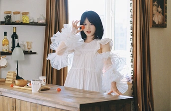 一个穿着白色连衣裙的年轻女子站在厨房里