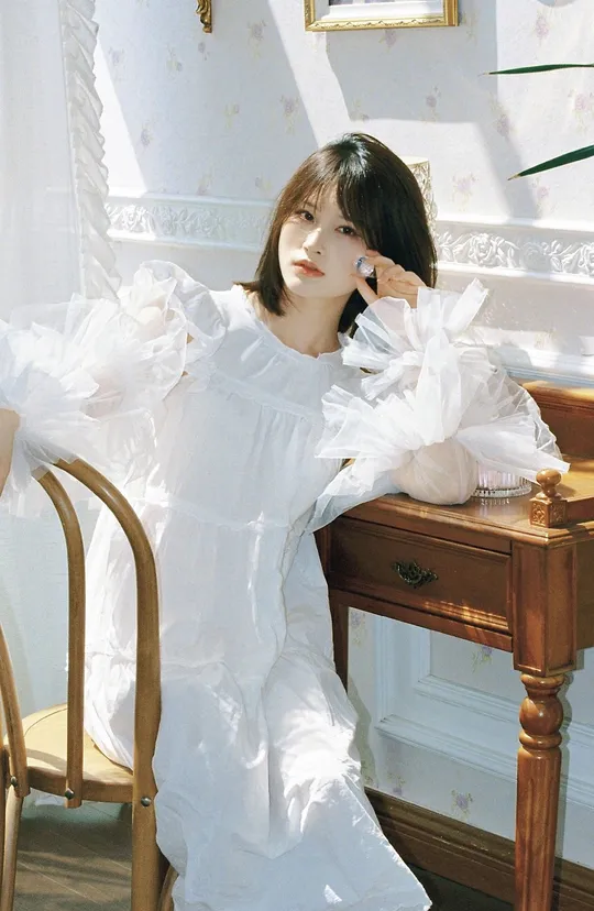 一个穿着白色连衣裙的年轻女子坐在椅子上打电话