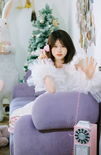 一个小女孩坐在紫色的椅子上拿着一个粉色手机