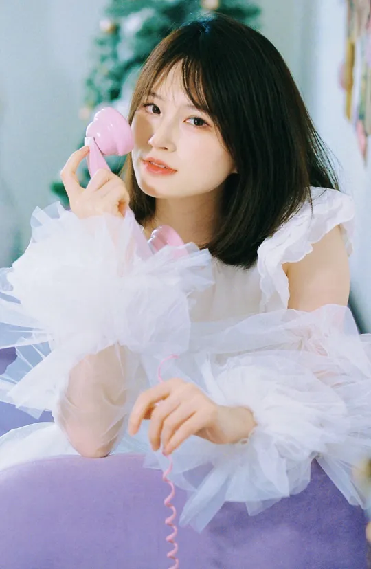 一个穿白色裙子的女孩正在粉色手机上讲话