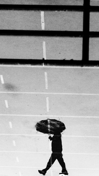 一个人在雨中穿过街道 手里拿着伞。