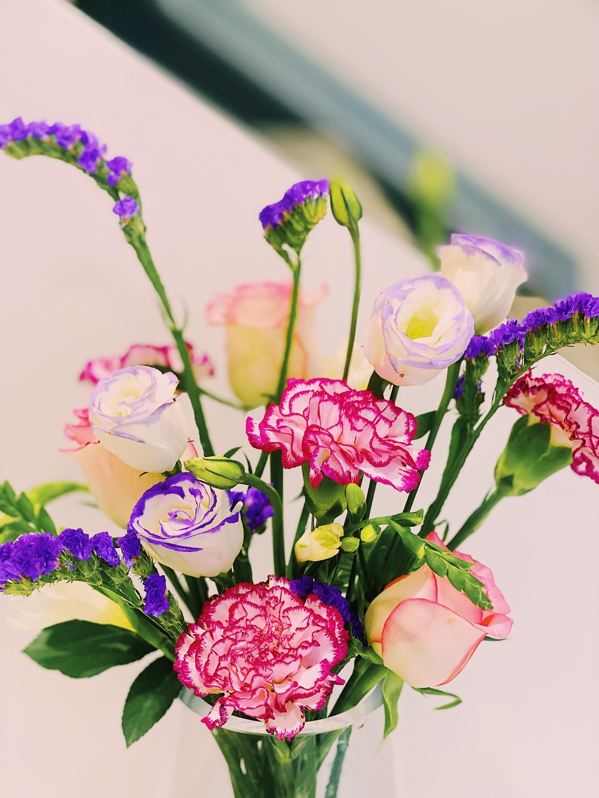 一个装满彩色花束的清晰花瓶 放在一张白色的桌子上