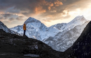 一个人站在山顶的雪景中 夕阳西下