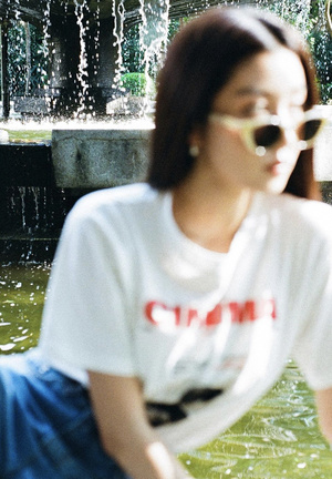 一个戴着墨镜的年轻女子坐在公园的池塘上