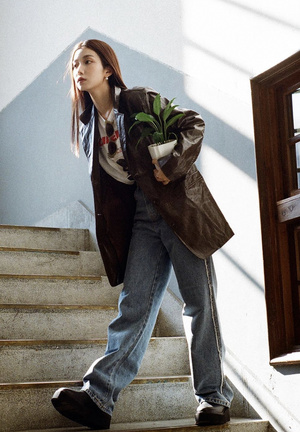 一个年轻的女人拿着一株植物和一个棕色的袋子走上楼梯