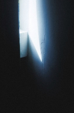 一间黑暗的房间 门开着 墙上有一条裂缝 光线透过