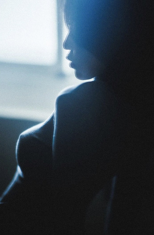 一个女人在黑暗的房间里向窗外望去的侧影