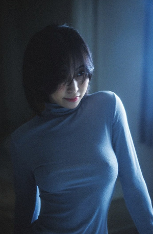一个穿着蓝色毛衣的年轻女人站在一个黑暗的房间里
