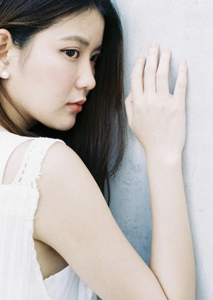 一位年轻女子倚靠在白色墙壁上 手捂住脸部