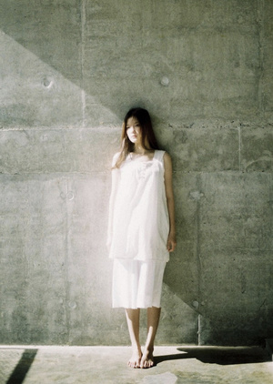 一位穿着白色连衣裙的年轻女子站在一块混凝土墙上