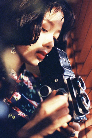 一位年轻女子站在镜子前拿着相机