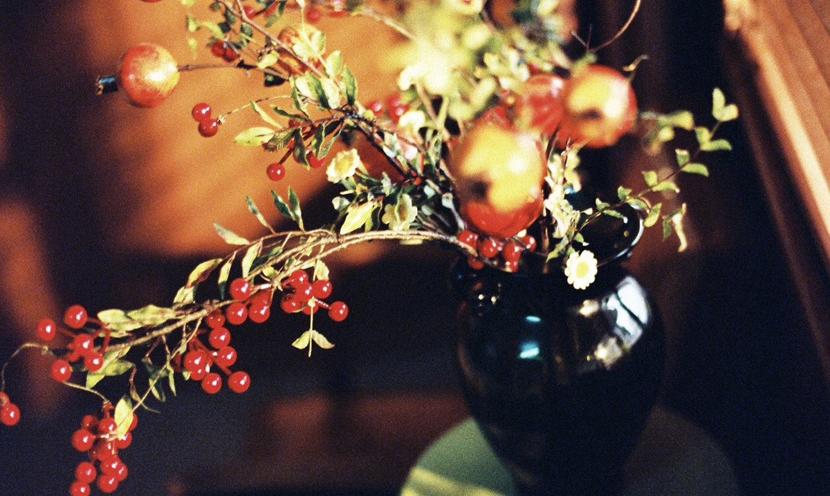 一个装满红果实的黑色花瓶 放在桌子上