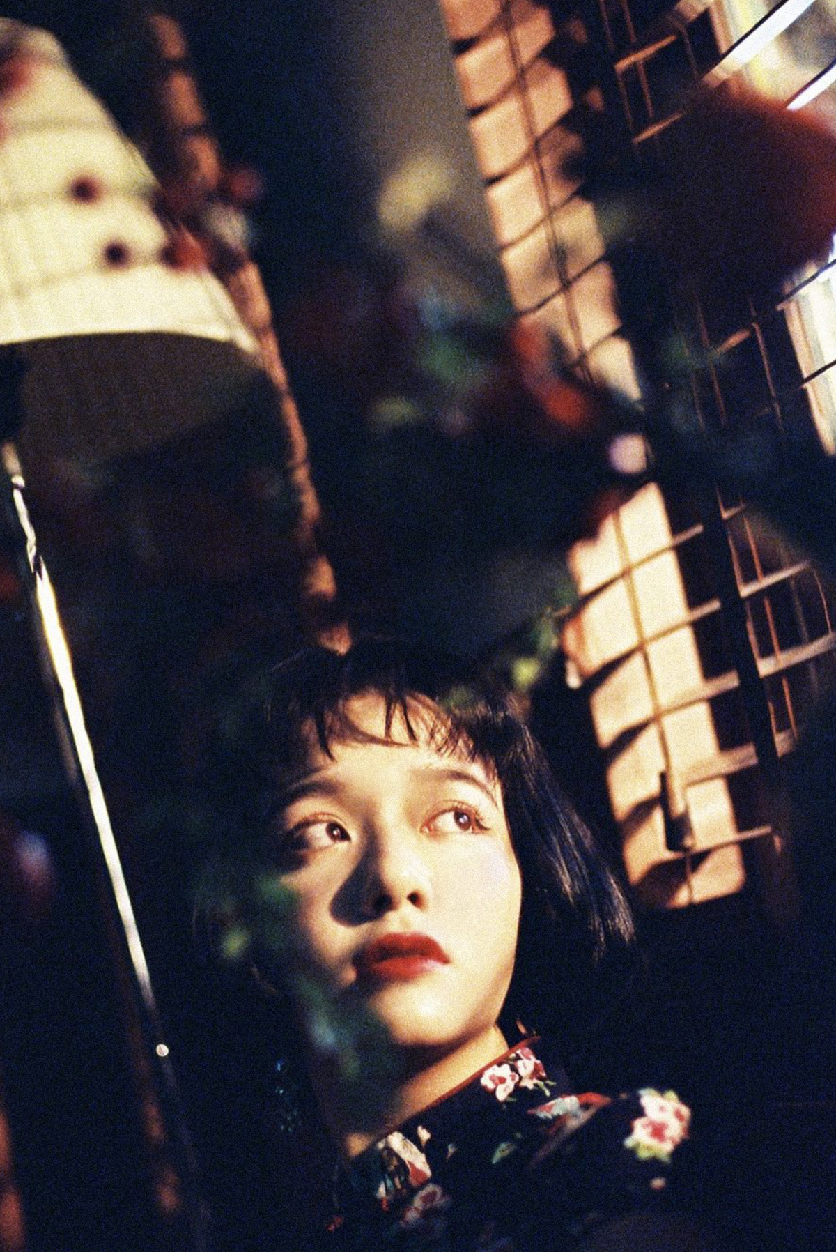 一个年轻男孩坐在灯下 透过窗户看着一个小女孩。