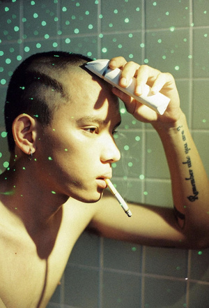 一个有纹身的年轻人 正在抽烟 并口中含着牙刷。
