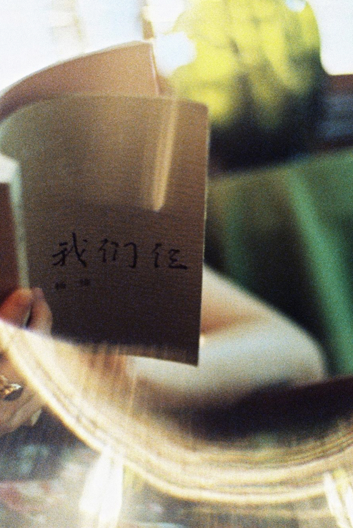 镜子里的人拿着一个有纸条的咖啡杯站在窗前