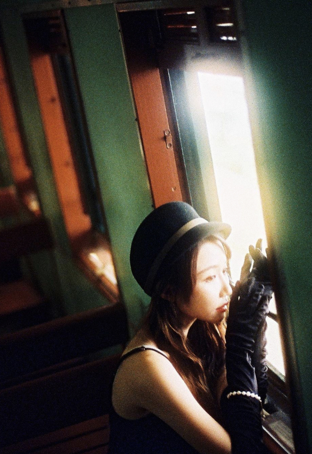一位年轻女子戴着黑色帽子手套凝视着火车窗户