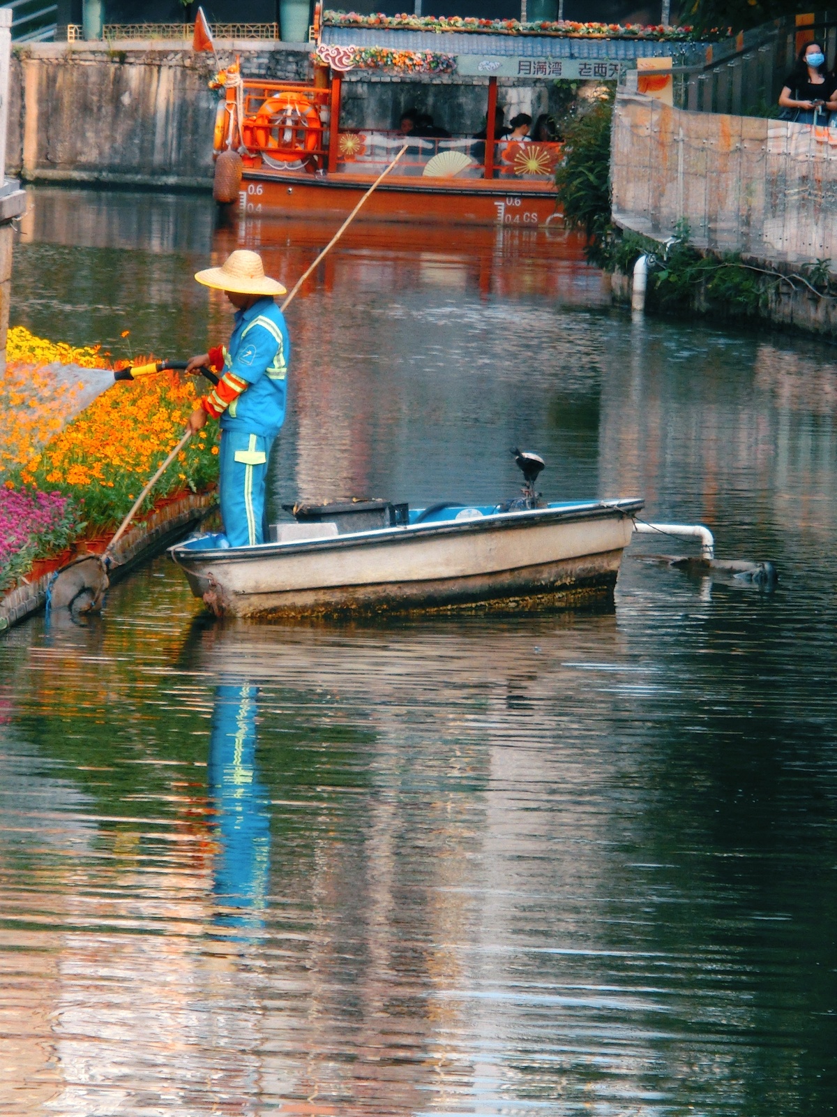 一位戴帽子的男人在一条小船上钓鱼 船在水上运河中。