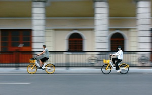 一个人骑着黄色的自行车沿着建筑物旁边的街道