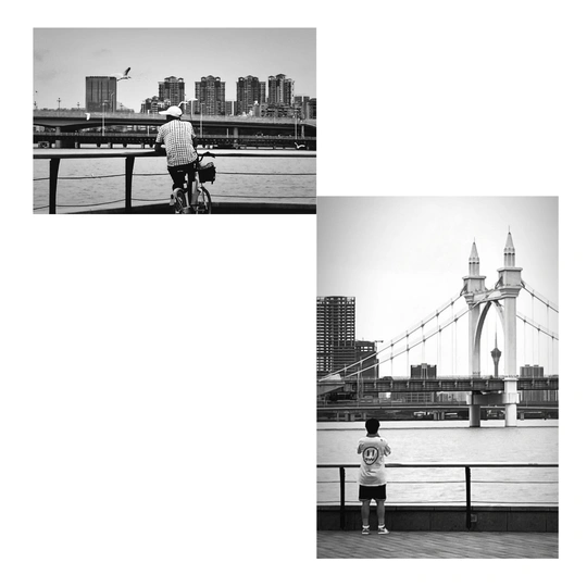 一张黑白照片 河上有一座桥 一个人骑自行车 一个人站在自行车上。