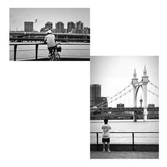 一张黑白照片 河上有一座桥 一个人骑自行车 一个人站在自行车上。