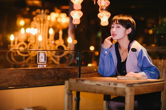 一个年轻女子坐在餐厅或酒吧的桌子旁 背景有灯光。