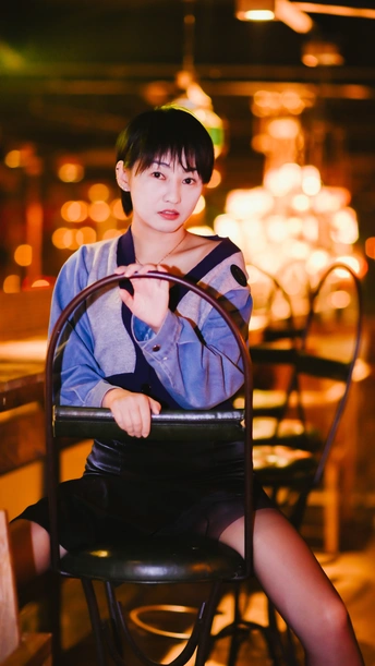 一个年轻女子坐在一家餐厅的桌子旁 坐在黑色椅子上。