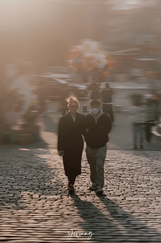 一个模糊的男人和女人在戴口罩的情况下走下鹅卵石街道