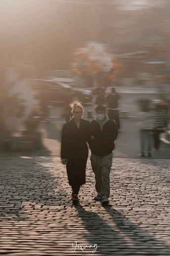 一个模糊的男人和女人在戴口罩的情况下走下鹅卵石街道