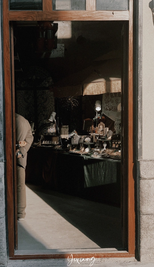 一个人站在一扇门边 透过建筑物的窗户看进去。