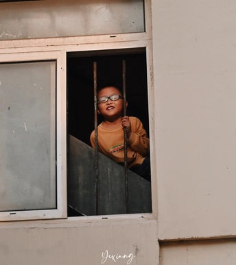 戴眼镜的女孩正在一栋建筑物的开窗处向外看