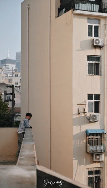 一个年轻人站在阳台上 眺望着一座高楼林立的都市。