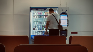 一个人站在饮料贩卖机前 正在看饮料