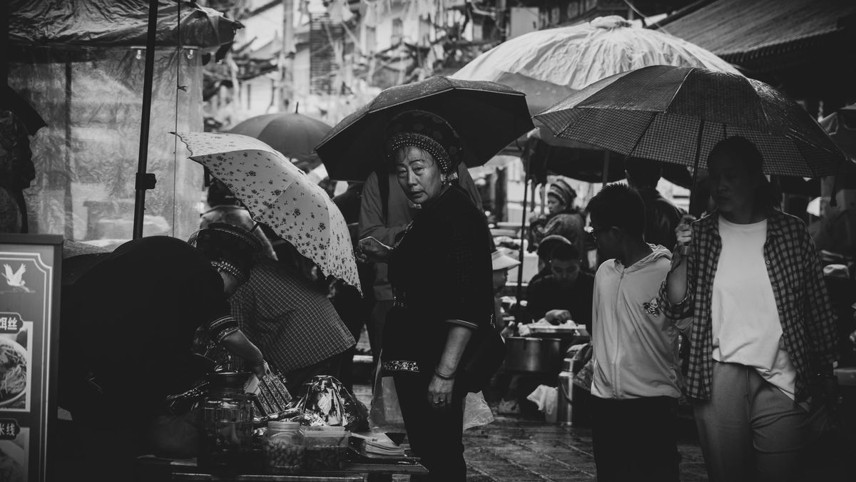 人们打着伞在雨中走人行道