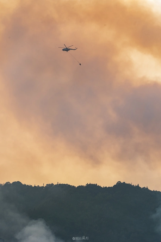 一架飞机和直升机在多云的天空中飞行 背景是橙色的烟雾和山丘