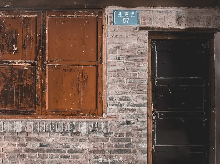 一座古老的砖楼 有一辆红色的消防栓 一扇木门和一扇窗户。