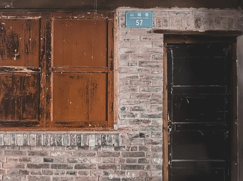 一座古老的砖楼 有一辆红色的消防栓 一扇木门和一扇窗户。