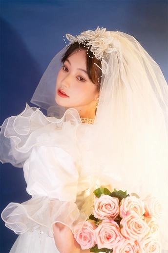 一位穿着白色连衣裙和面纱的女士 手拿一束粉色玫瑰花的花像。