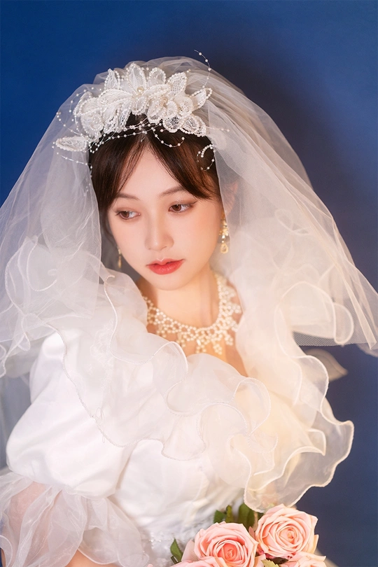 一位年轻女子穿着白色连衣裙和面纱 背景为粉红色玫瑰花图案的蓝色背景照片