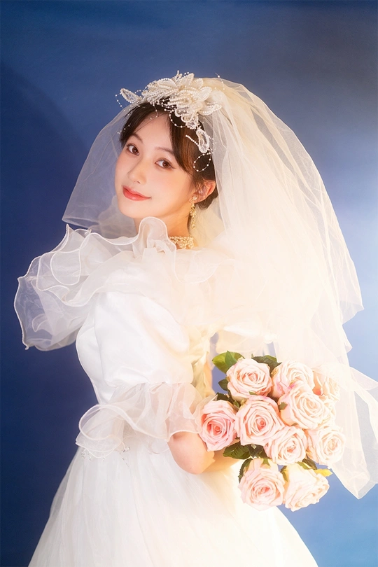 一位年轻女子穿着白色连衣裙和头纱 手拿粉色玫瑰花束的肖像。