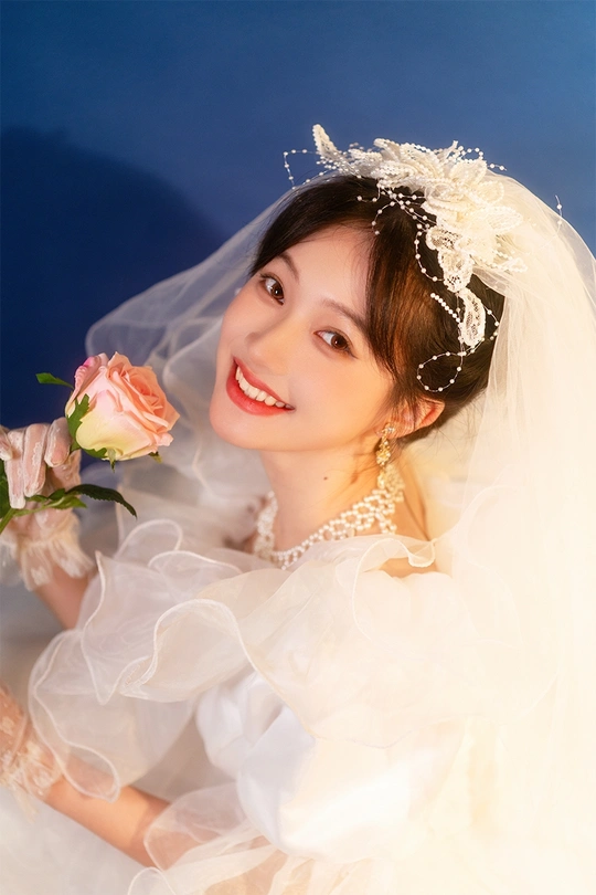 一位年轻女子穿着白色连衣裙和头纱 手拿玫瑰的肖像。