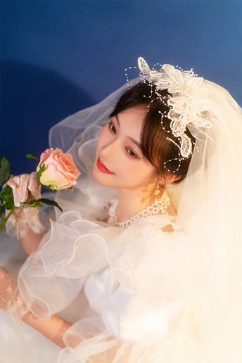 一位年轻女子穿着白色连衣裙和头纱 手拿玫瑰的肖像。