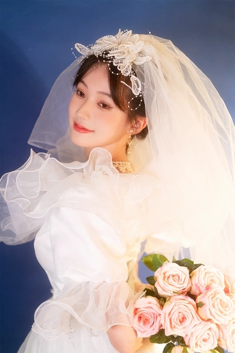 一位年轻女子穿着白色连衣裙和头纱 手拿粉色玫瑰花束的肖像。