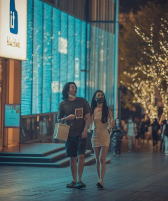 一对年轻男女晚上走在城市的人行道上