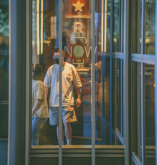 一男一女穿过一栋建筑的玻璃门穿过一家商店的倒影
