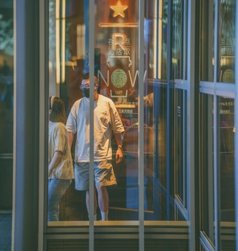 一男一女穿过一栋建筑的玻璃门穿过一家商店的倒影