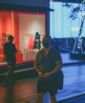 晚上 一个双臂交叉的男人站在一家商店的橱窗前